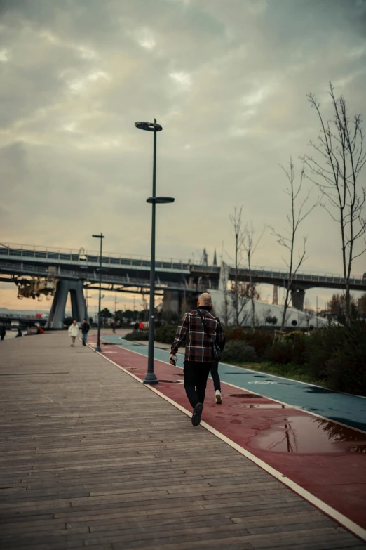 a man riding a skateboard down a wooden walkway, inspired by Elsa Bleda, happening, shipyard, istanbul, walking at the park, sky bridge