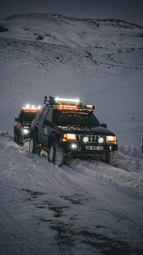 a couple of trucks driving down a snow covered road, glowing headlights, off-roading, profile image, glacier