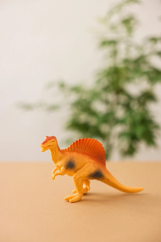 a close up of a toy dinosaur on a table, inspired by Adam Rex, trending on unsplash, figuration libre, orange fluffy spines, japanese collection product, 1 9 8 9, natural history