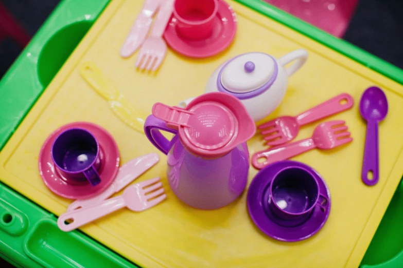 a green tray topped with pink and purple plastic utensils, inspired by Toyen, unsplash, seinfeld fancy tea party, softplay, pink and yellow, middle close up