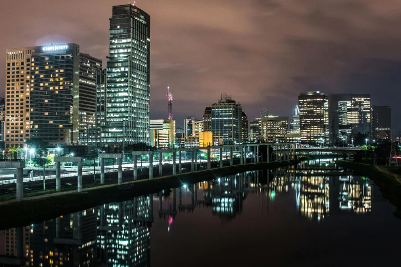 a river running through a city next to tall buildings, by Lee Loughridge, pexels contest winner, hurufiyya, chilean, city light reflections, panoramic, fan favorite