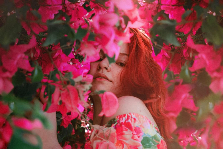 a woman with red hair standing in front of pink flowers, inspired by Elsa Bleda, pexels contest winner, made of flowers and leaves, girl in a bed of flowers, glowing red, center of image