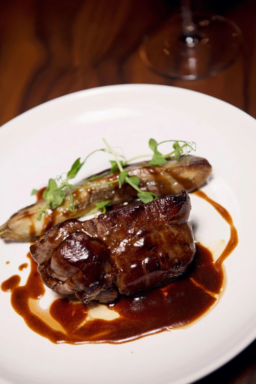 a white plate topped with meat covered in sauce, by Robbie Trevino, renaissance, chef table, glazed, skewed shot, jen yoon