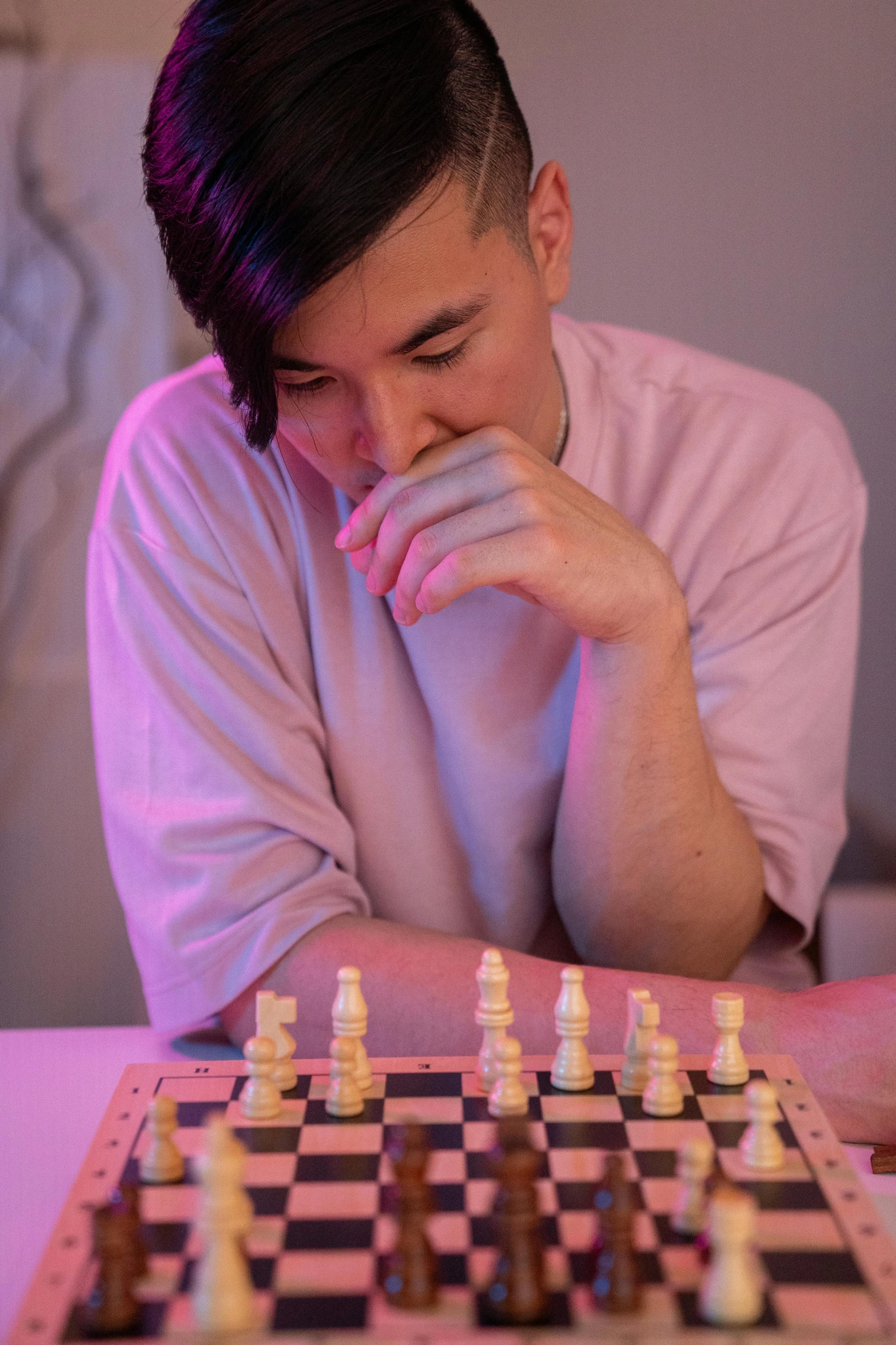 a man sitting at a table with a chess board, bisexual lighting, profile image, ross tan, wearing a light - pink suit