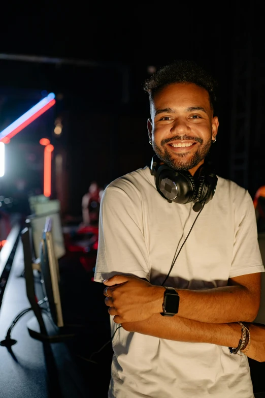 a man with headphones standing in front of a microphone, in a nightclub, smiling into the camera, 2019 trending photo, mixed race