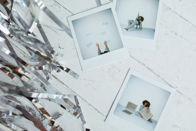a bunch of polaroids sitting on top of a table, inspired by Elsa Bleda, trending on pexels, shiny silver, on a pale background, an artistic pose, square pictureframes