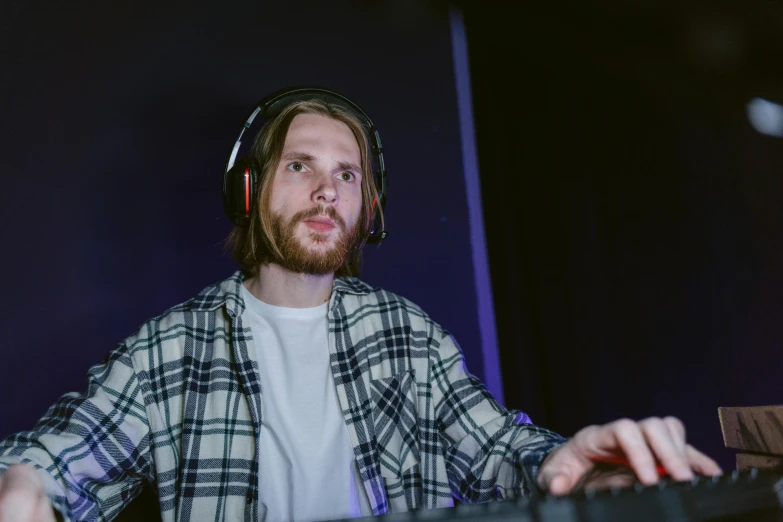 a man wearing headphones sitting in front of a keyboard, light beard, with professional lighting, thumbnail, no watermarks