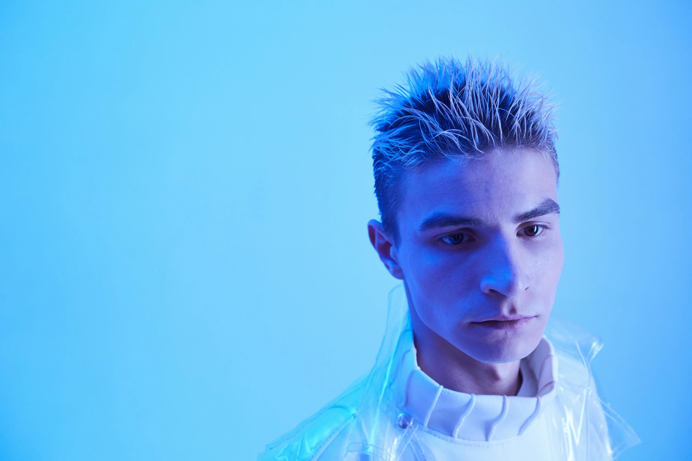 a man with spiky hair standing in front of a blue background, an album cover, inspired by Kristian Kreković, trending on pexels, antipodeans, white cyborg fashion shot, high blue lights, catalog photo, teenage boy