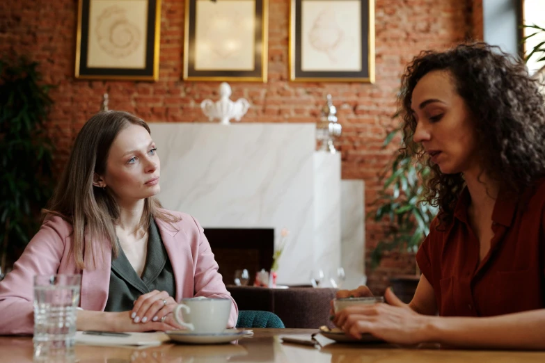 two women sitting at a table talking to each other, pexels, sitting on a mocha-colored table, 15081959 21121991 01012000 4k, looking serious, professional image