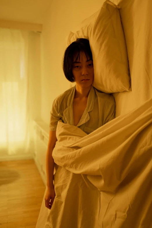 a woman standing next to a bed covered in a sheet, by Fei Danxu, 8 k movie still, soft light - n 9, comforting, in a hotel hallway