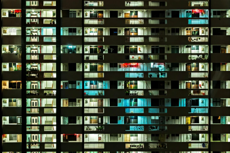 a tall building with lots of windows lit up at night, inspired by Andreas Gursky, pexels contest winner, brutalism, soviet apartment buildings, cyan shutters on windows, people at night, a colorful