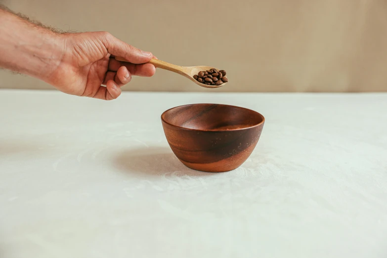a person holding a wooden spoon over a bowl, inspired by Kawai Gyokudō, long coffee brown hair, red sand, matt finish, moroccan