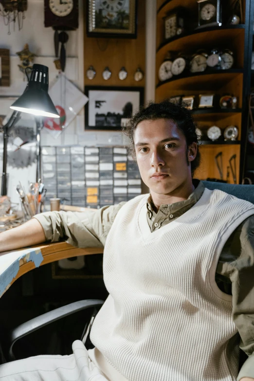 a man sitting at a desk in front of a computer, a character portrait, inspired by Julius Klinger, trending on pexels, weta workshop, adam driver, model is wearing techtical vest, in a workshop