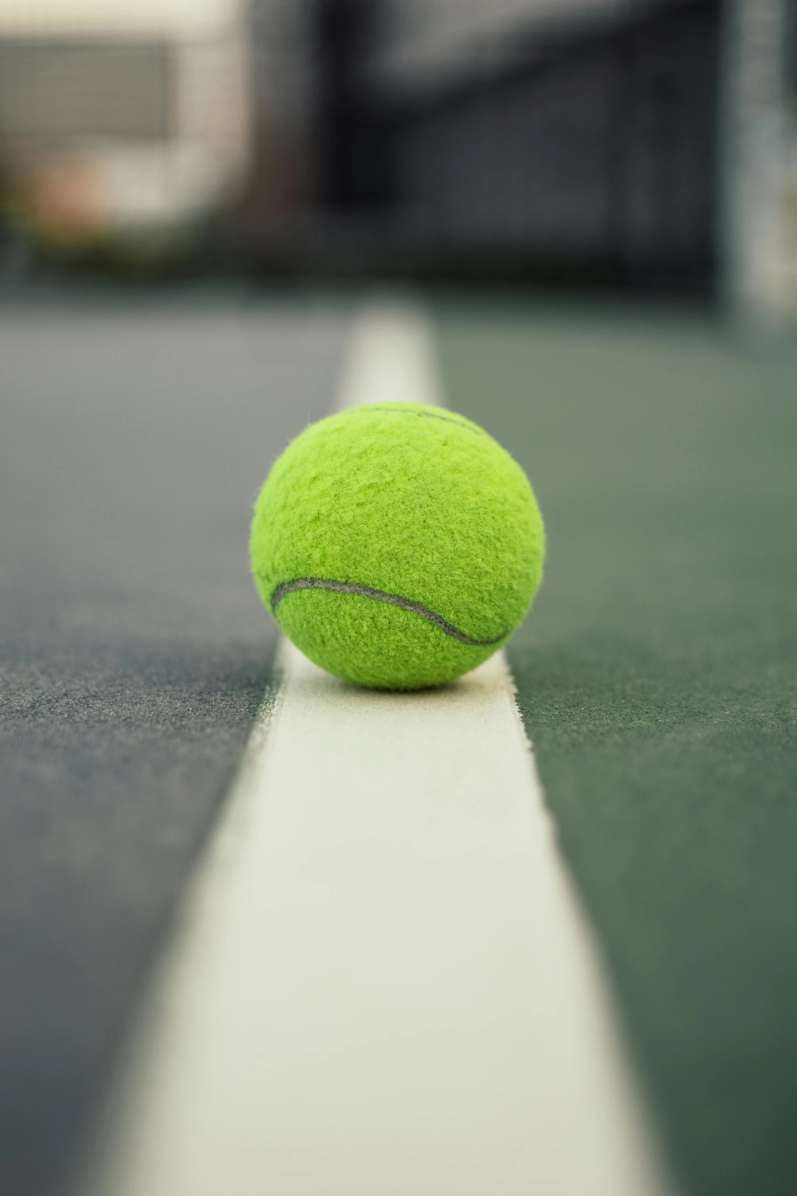 a tennis ball sitting on top of a tennis court, facing the camera