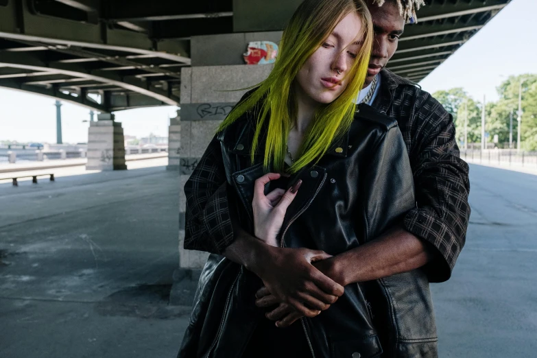 a man and a woman standing next to each other, inspired by Elsa Bleda, trending on pexels, visual art, bright green hair, yellow and charcoal leather, overpass, woman holding another woman