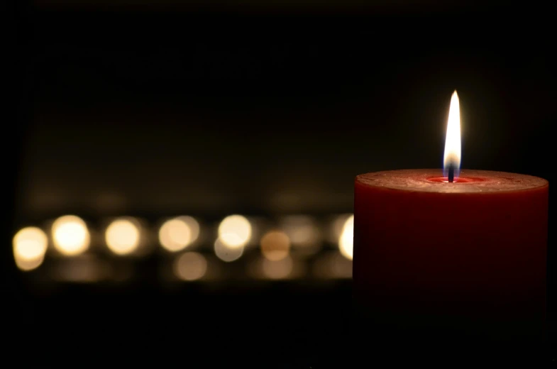 a red candle is lit in the dark, lights in distance, honored, getty images, family photo