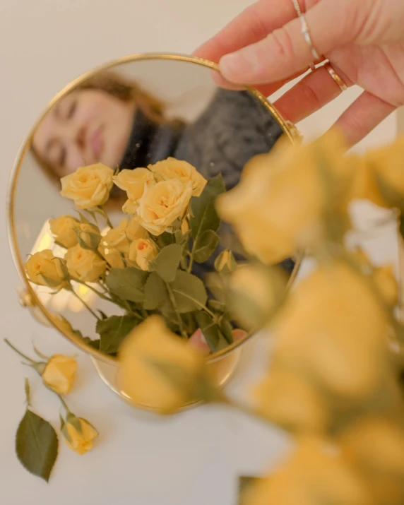 a person taking a picture of themselves in a mirror, a picture, inspired by Elsa Bleda, aestheticism, yellow rose, bouquet, product introduction photo