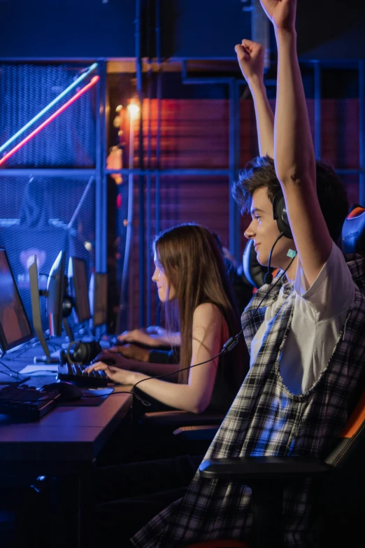 a group of people sitting in front of computers, video games, raising an arm, blue and red lights, header