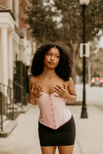 a woman in a pink corset standing on a sidewalk, by Dulah Marie Evans, trending on pexels, renaissance, black young woman, seductive lingerie camisole, curls on top, lorde