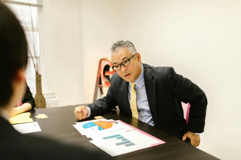 a man in a suit and tie sitting at a table, a cartoon, unsplash, shin hanga, wearing a suit and glasses, focused photo, ernie chan, meg kimura