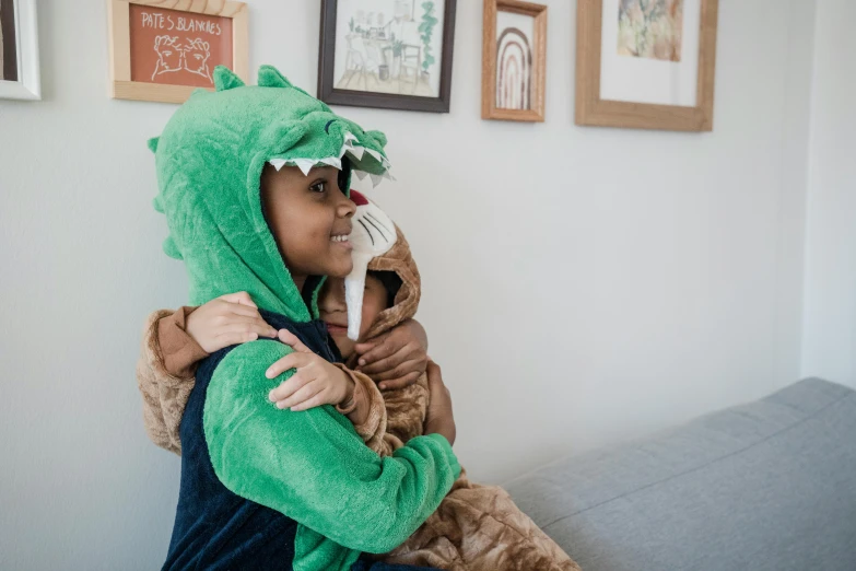 a woman in a dragon costume sitting on a couch, inspired by Abidin Dino, pexels contest winner, hurufiyya, hugging each other, toddler, green and brown clothes, plush toy