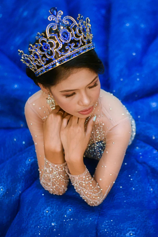 a woman in a blue dress with a crown on her head, an album cover, pexels contest winner, mai anh tran, shiny and sparkling, square, thumbnail