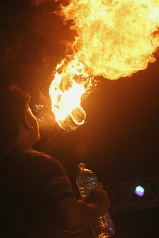 a man holding a bottle of water in front of a fire, fireball lighting her face, fire staff, “fire breathing dragon, taken in the late 2010s