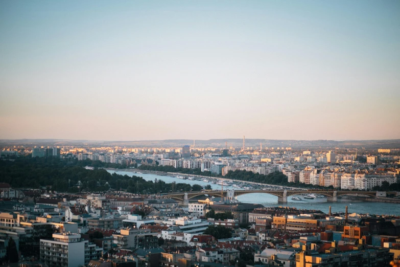 a view of a city from the top of a building, by Emma Andijewska, pexels contest winner, river in the background, evening light, plain background, slide show