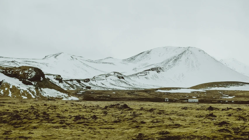 a field with snow covered mountains in the background, by Hallsteinn Sigurðsson, pexels contest winner, hurufiyya, background image, rocky hills, 2000s photo