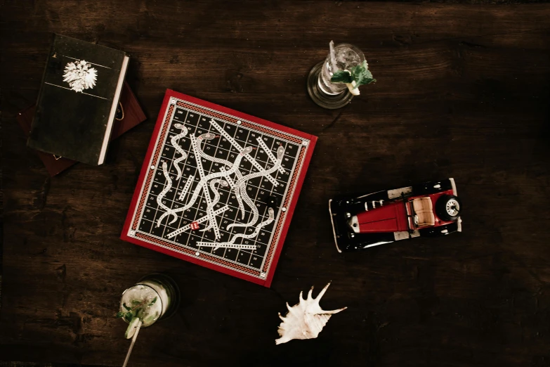 a wooden table topped with assorted items, an album cover, pexels contest winner, kinetic art, game board, scarlet, marauders map, high resolution product photo