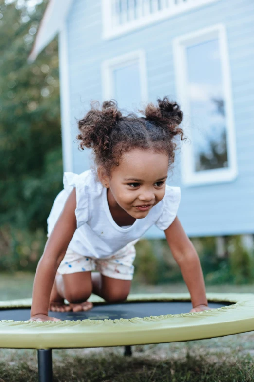 a little girl that is standing on a trampol, by Arabella Rankin, laying on her back, in the garden, playing games, varying ethnicities