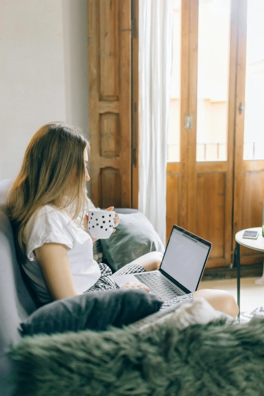 a woman sitting on a couch using a laptop, trending on pexels, happening, someone in home sits in bed, polka dot, natural light outside, 1 2 9 7