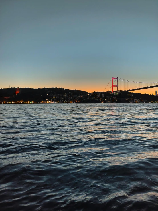 a body of water with a bridge in the background, a picture, pexels contest winner, hurufiyya, istanbul, sunset panorama, the photo was taken from a boat, 8k resolution”