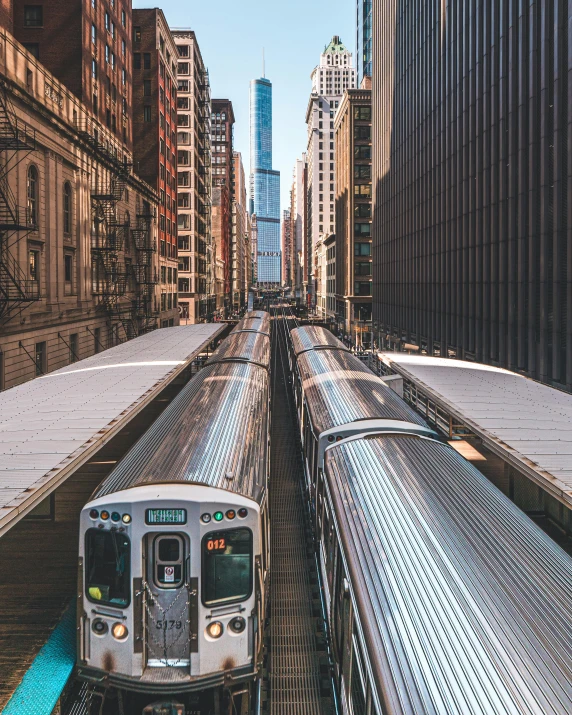 a train traveling through a city next to tall buildings, by Carey Morris, unsplash contest winner, chicago, lgbtq, instagram story, white pale concrete city