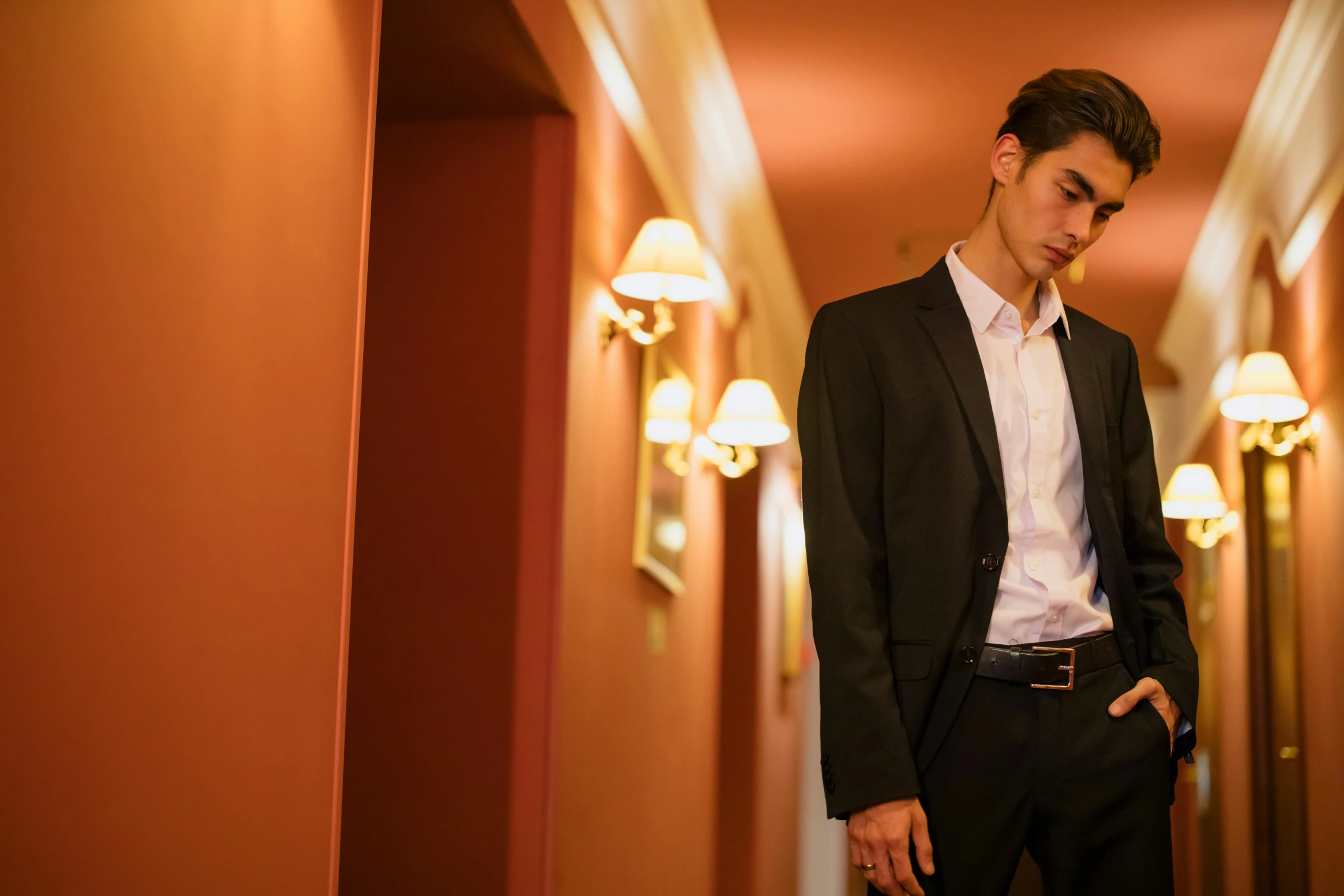 a man in a suit standing in a hallway, trending on pexels, male teenager, delicate androgynous prince, evening time, sad scene