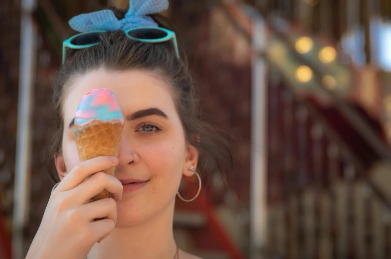 a woman holding an ice cream cone in front of her face, pexels contest winner, photorealism, pink and blue colour, maisie williams, theme park, food commercial 4 k