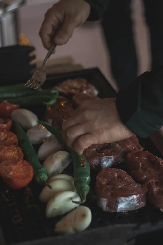 a close up of a person cooking food on a grill, offering a plate of food, vegetables, beefy, patagonian