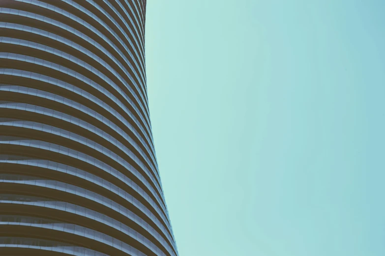 a tall building with a blue sky in the background, an album cover, inspired by Zaha Hadid, unsplash contest winner, minimalism, curved furniture, desaturated colours, detail texture, cyan