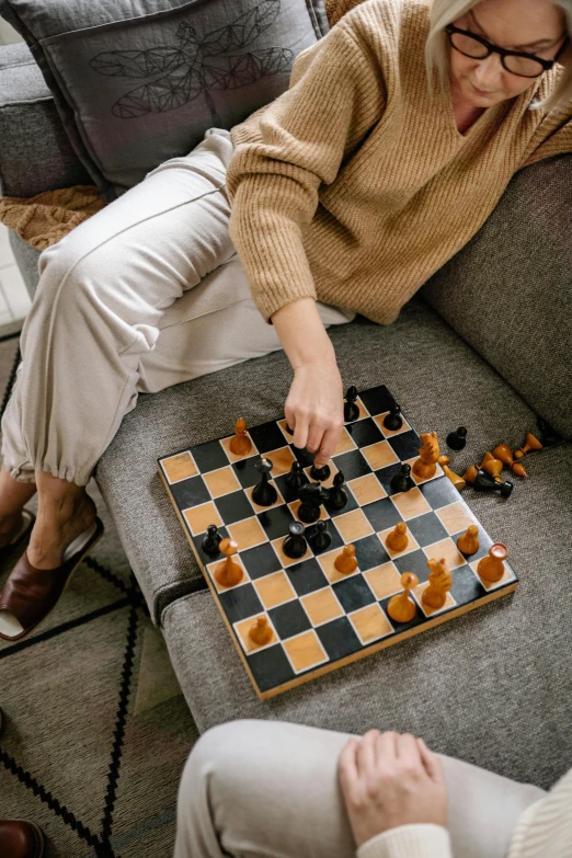 a woman sitting on a couch playing a game of chess, curated collections, square, thumbnail, tabletop