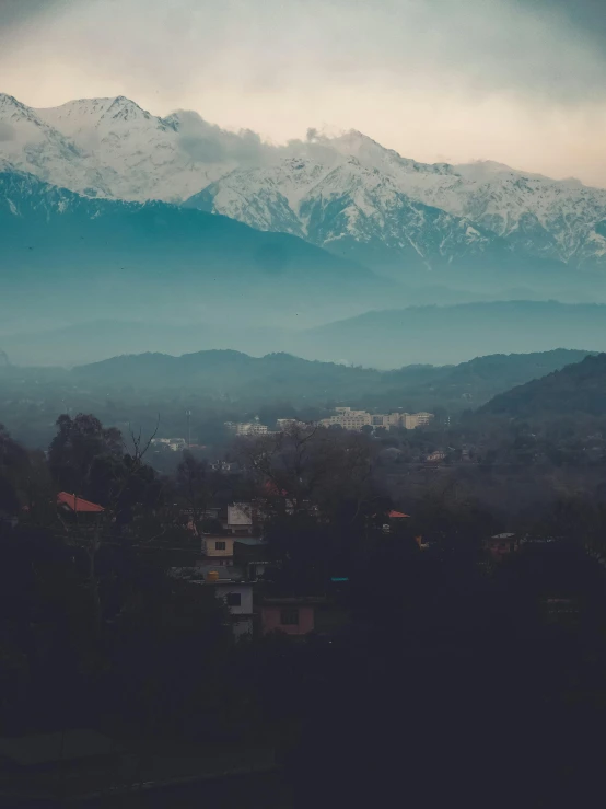 a view of a mountain range in the distance, pexels contest winner, village in the background, cold hues, background image, hazy and dreary