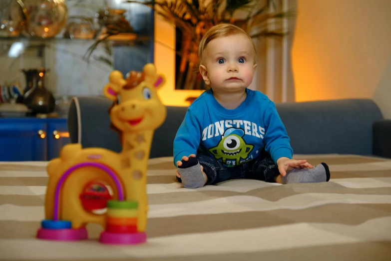 a baby sitting on a bed next to a toy giraffe, a cartoon, by Hristofor Zhefarovich, pexels contest winner, monsters in the background, indoor picture, casually dressed, very handsome