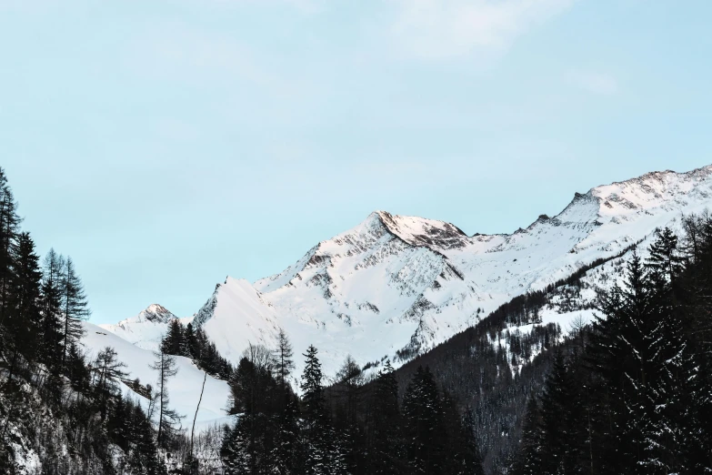 a group of people riding skis down a snow covered slope, tall mountains, hill with trees, unsplash photography, minimalistic art