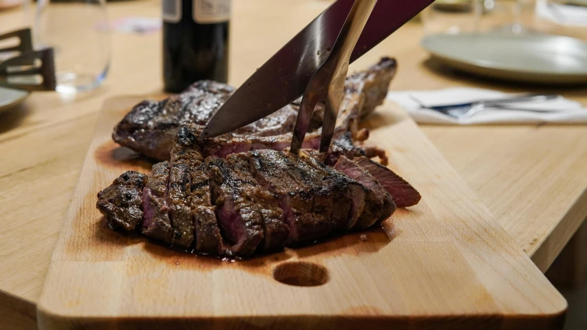 a wooden cutting board topped with steak and a knife, by Daniel Lieske, drinking, saturno buttò, burned, medium angle