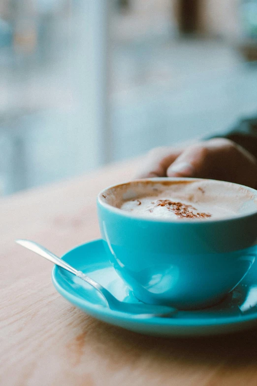 a person sitting at a table with a cup of coffee, pexels contest winner, brown and cyan blue color scheme, melbourne, cappuccino, soup