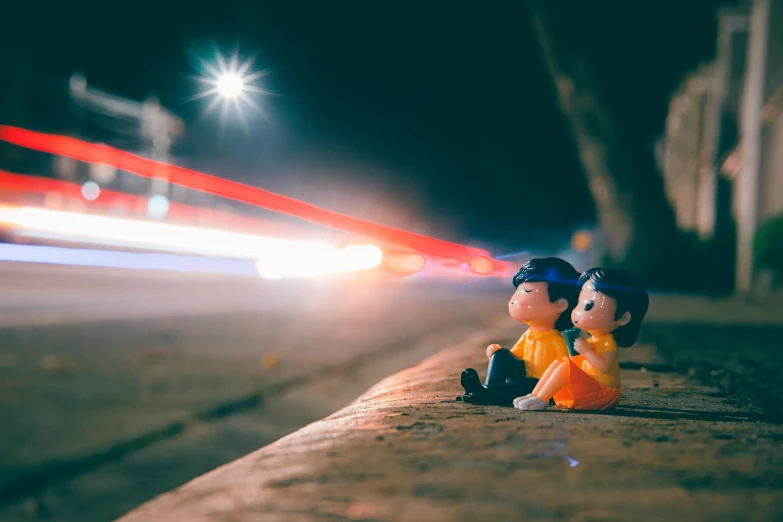 a couple of figurines sitting on the side of a road, by Niko Henrichon, pexels contest winner, magical realism, search lights, toy photo, 35mm of a very cute, laser beam ; outdoor