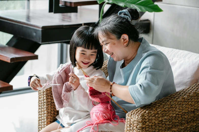 a woman sitting next to a little girl on a couch, a cross stitch, inspired by Cui Bai, pexels contest winner, sustainable materials, avatar image, yarn ball, joy ang