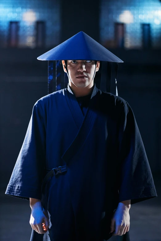 a man wearing a blue hat and holding a knife, inspired by Gu An, shin hanga, tech robes, **cinematic, ao dai, dramatic sci-fi movie still