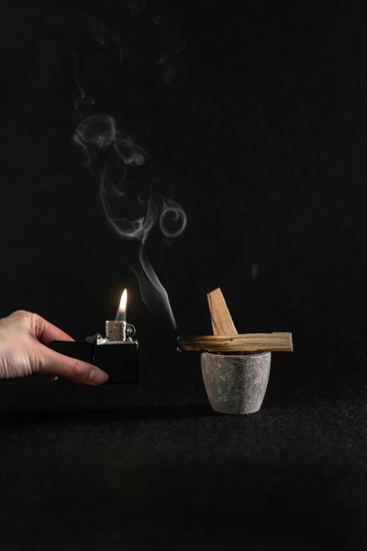 a person holding a cigarette with smoke coming out of it, a still life, inspired by Kaigetsudō Ando, unsplash, smouldering charred timber, on a candle holder, light grey mist, on black background