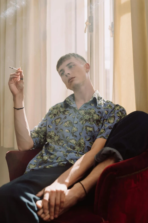 a man sitting in a chair smoking a cigarette, an album cover, by Jessie Alexandra Dick, trending on pexels, hawaiian shirt, delicate androgynous prince, smooth pale skin, patterned clothing