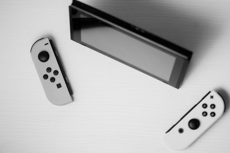 a couple of remotes sitting on top of a table, a black and white photo, minimalism, nintendo switch, cinematic outfit photo, realistic »